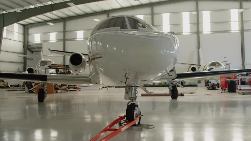 The white plane is parked in the hangar on a sunny day