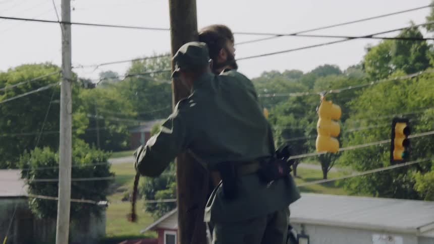 A military officer ties a man to a wood post