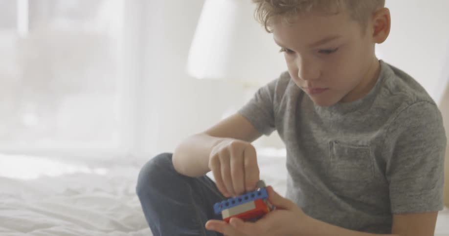 Boy plays with blocks on a bed
