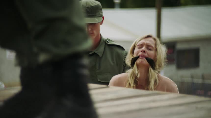 Soldier standing next to an upset women with a gag in her mouth