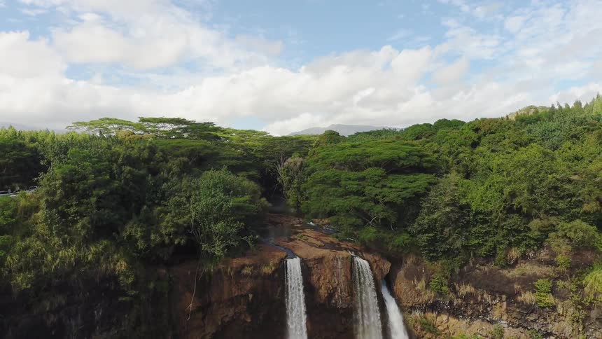 A waterfall is cascading over a cliff in a natural landscape during the day