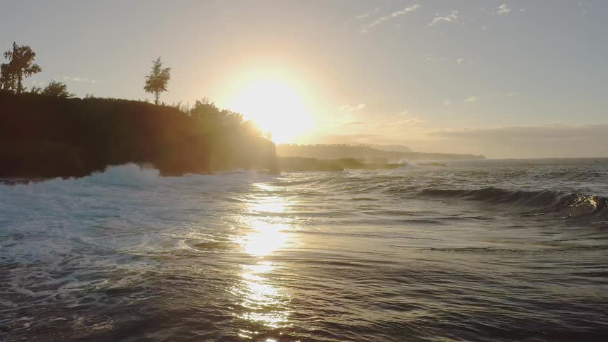 Sun shines over water splashing on a beach