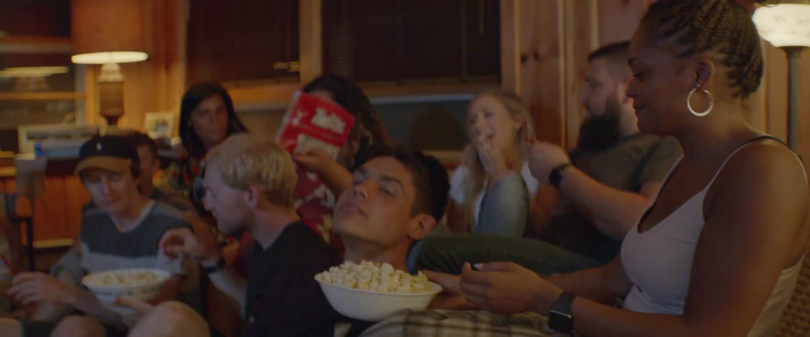 A group of people eat popcorn while watching tv together