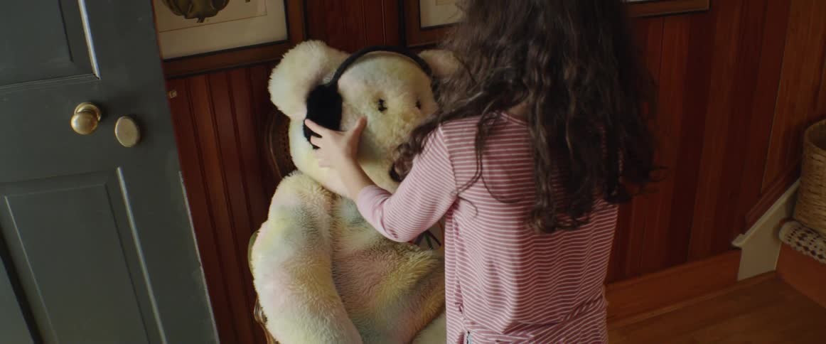A child puts earmuffs on a teddy bear