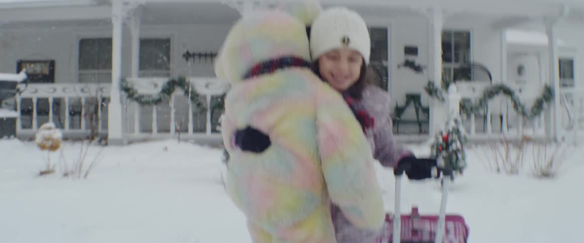 A child carries a teddy bear from the house