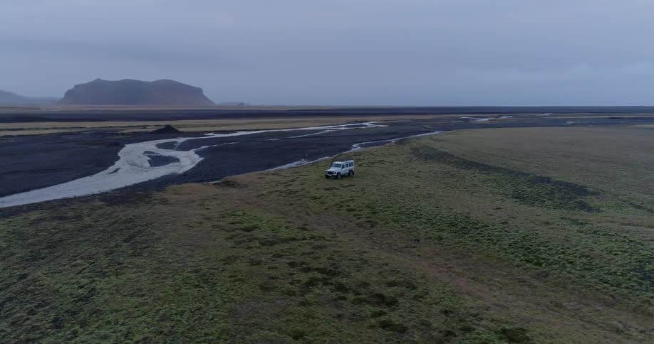 The vehicle races past the stream on the field