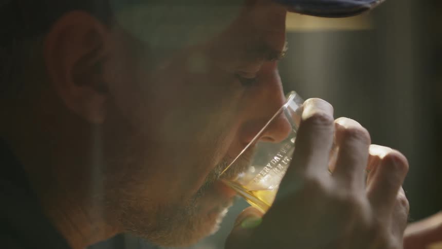 The man takes a drink from his glass
