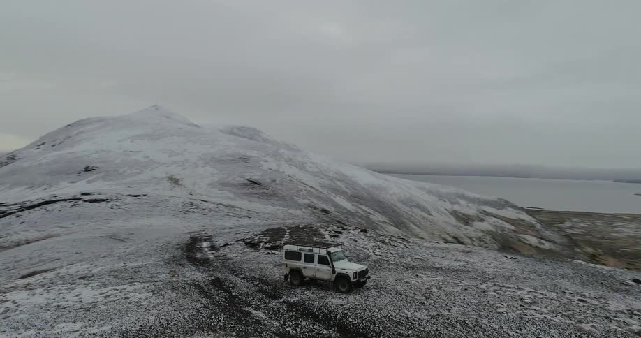 Vehicle pulling off a path in a hilly and barren area on a cloudy day