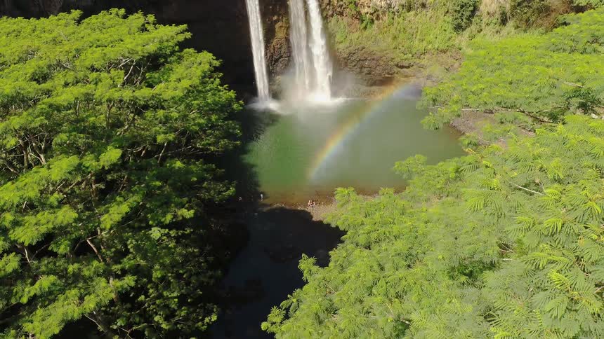 Waterfall splashing into a river with a rainbow shining overhead