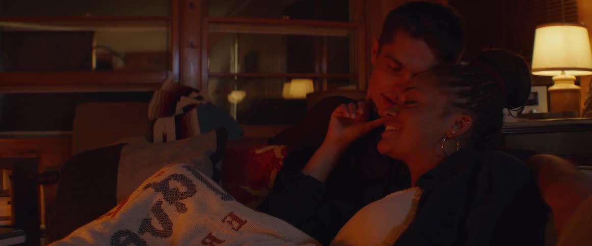 Man and woman sit together on a couch at night talking