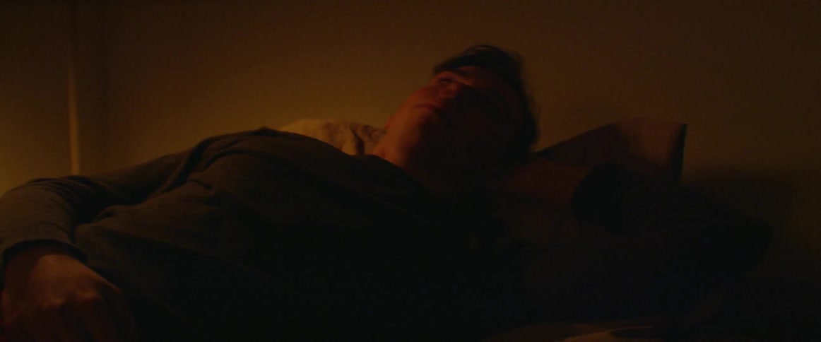 Man lays in a bed and turns his head