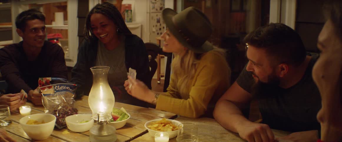 Men and women sitting at a table laughing and playing cards