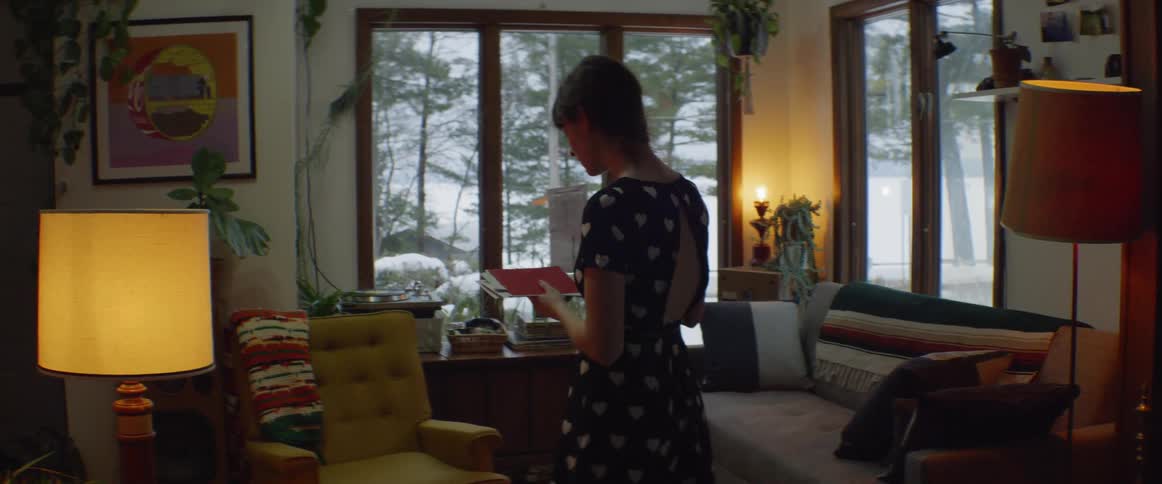 A woman walks in her living room looking at mail