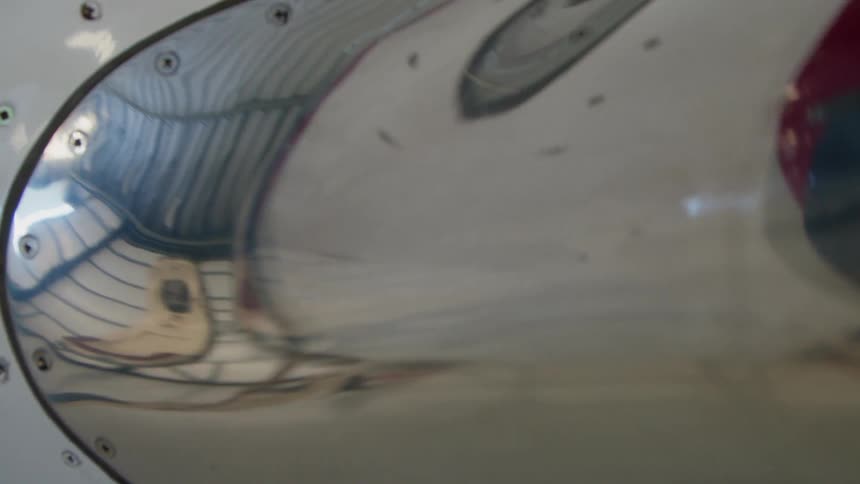 The metal surface of an airplane wing reflects the hangar it is in