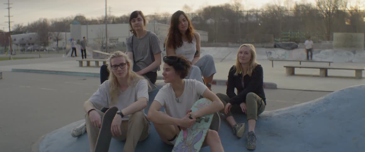 Group of teenagers are sitting with skateboards at skate park
