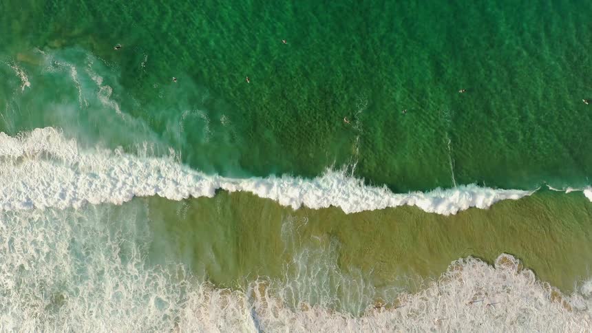 The green waters crash against the sand