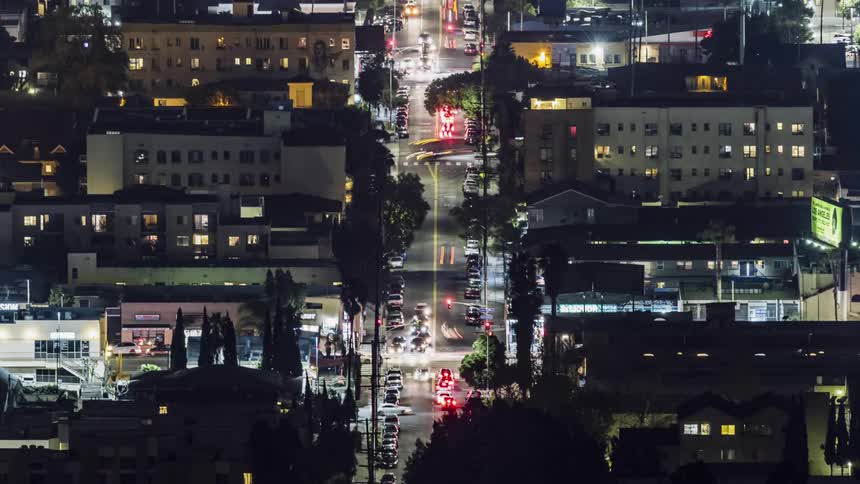 The town street is lit up with moving cars