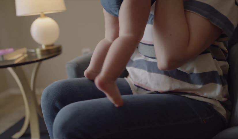 A woman sits on a chair as she plays with a baby