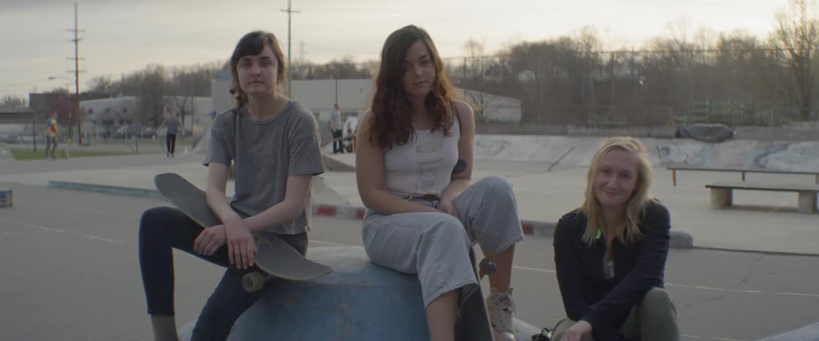 Three teenage girls sit in a skate park