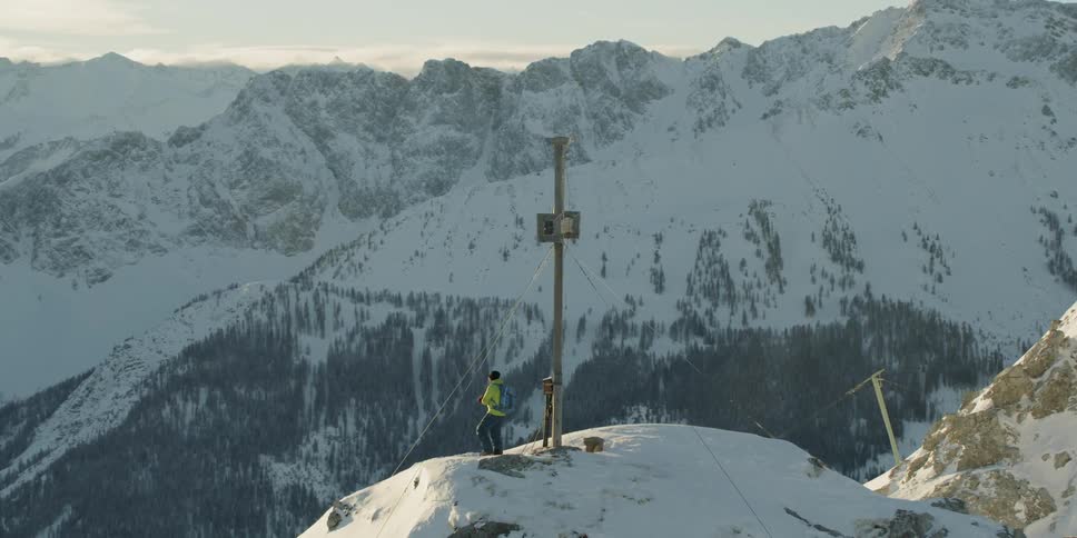 A hiker stands on a snowy mountain peak