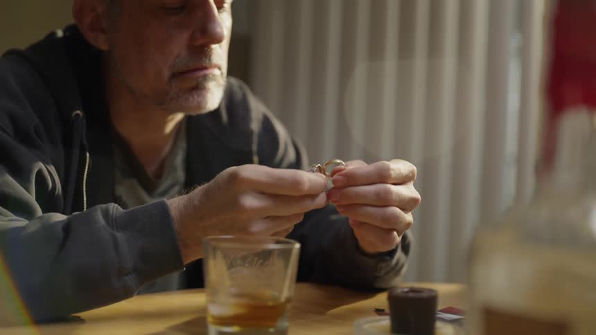 Man sits at a table holding two rings