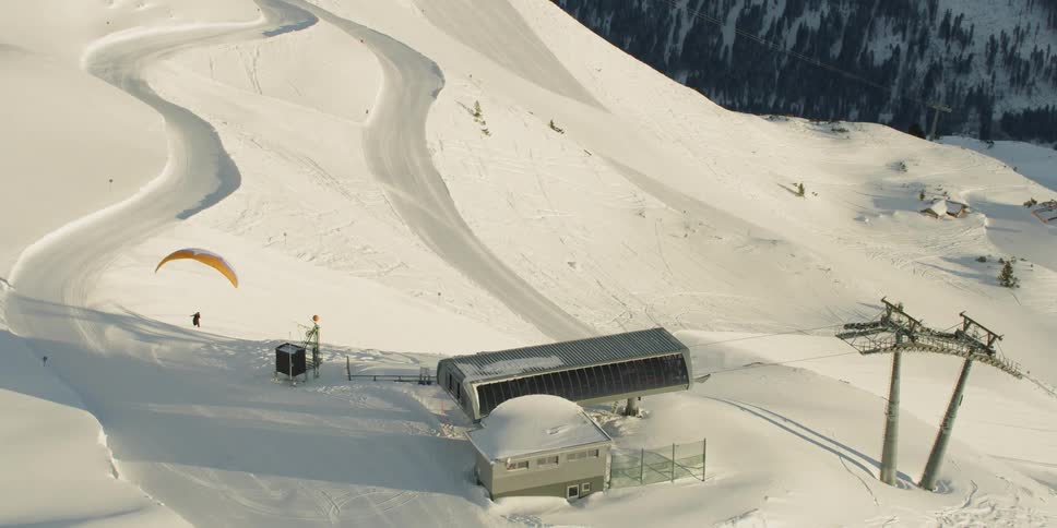Person is hang gliding at snow covered mountain ski resort