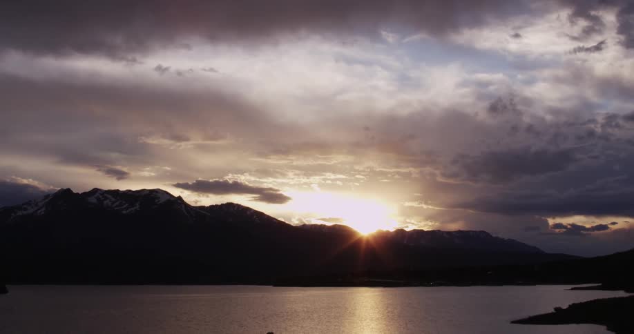 View of a sunset sinking behind the hills with a lake in front of it