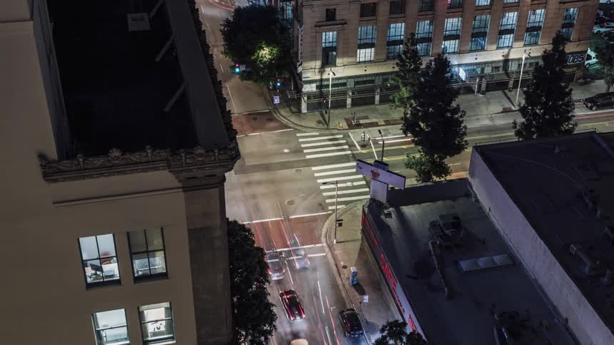 Cars race through the intersection in the city below