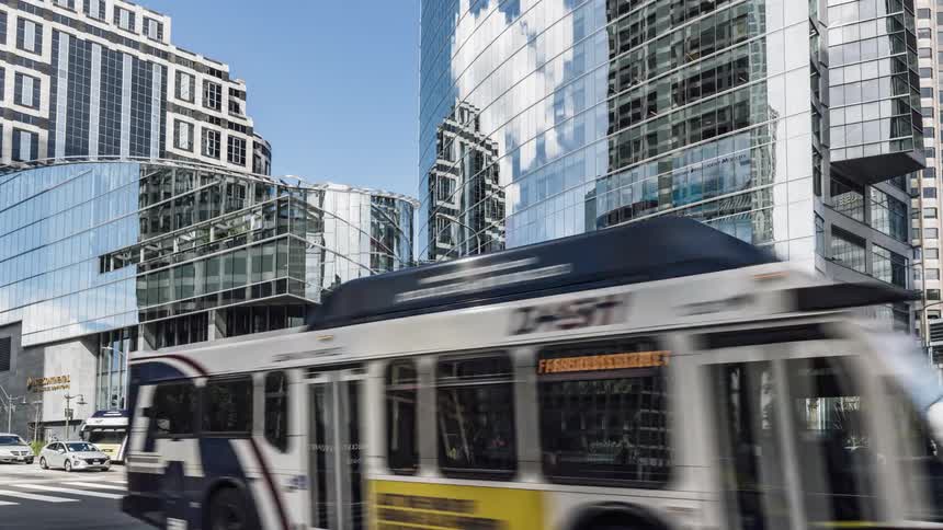 Traffic travels down a street under a blue sky