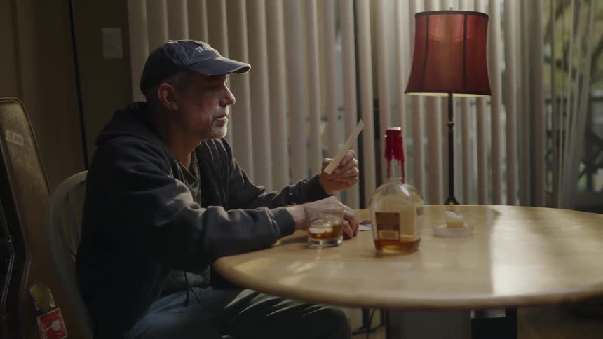Man sits at a table looking at a photograph