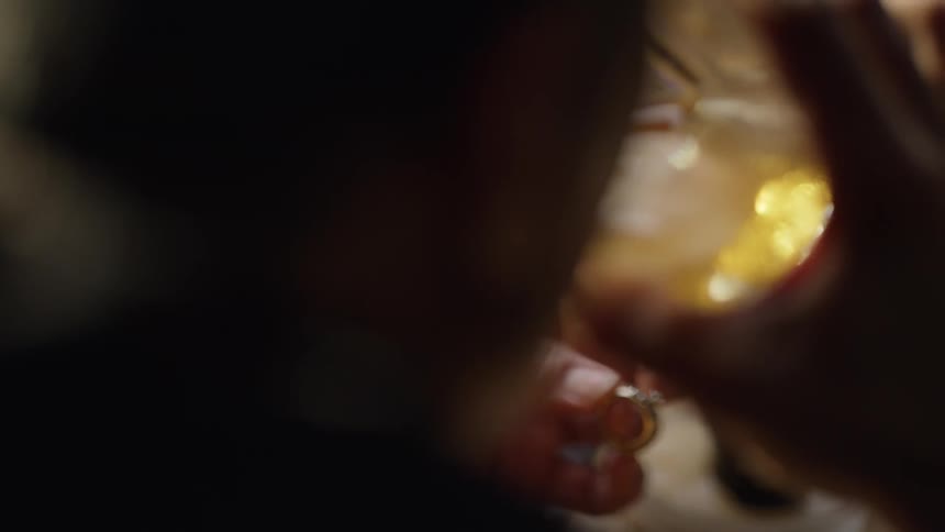 Man looking at a ring and sipping from a glass