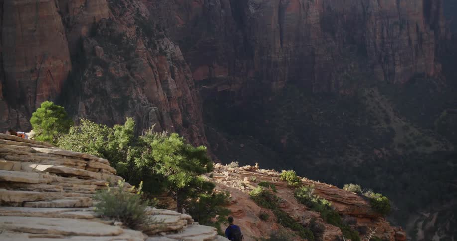 Steep cliff on a mountain range as a man walks to one edge