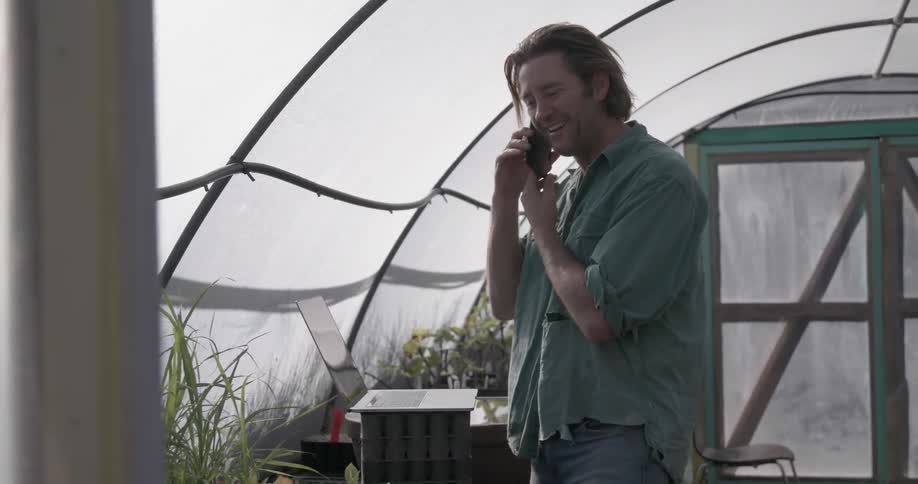 Man talks on the phone in a greenhouse