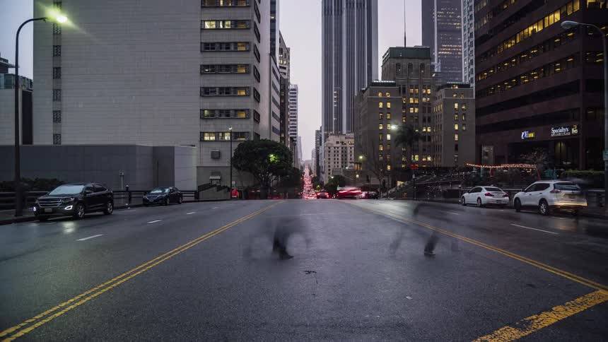 The cars drive down the road in the city at sunset