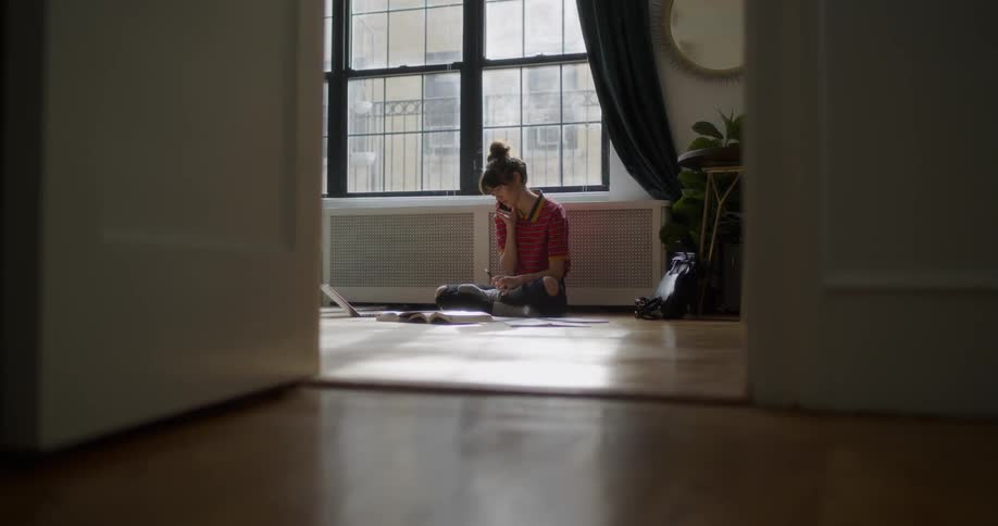 A woman sits on a floor using a phone