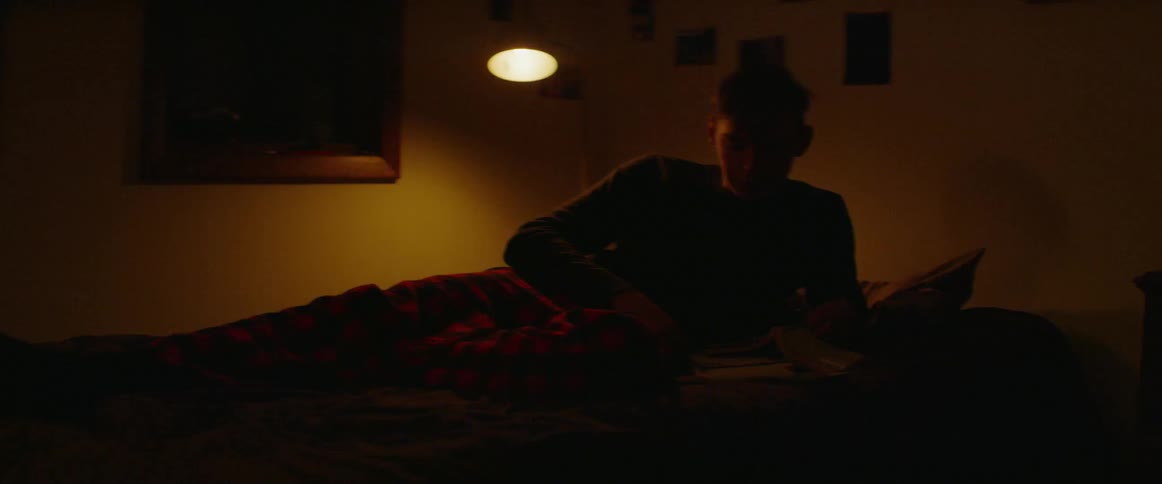 The man gets up to check his phone in bed