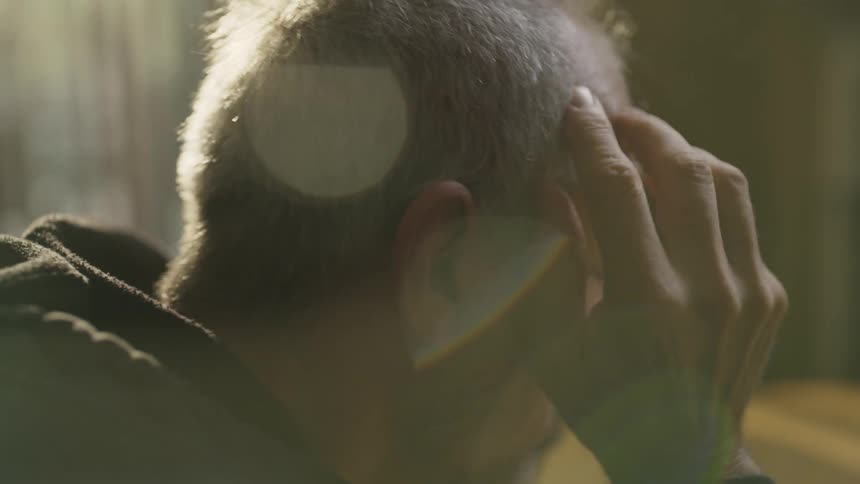 Man takes his hat off and rubs his head with his hands