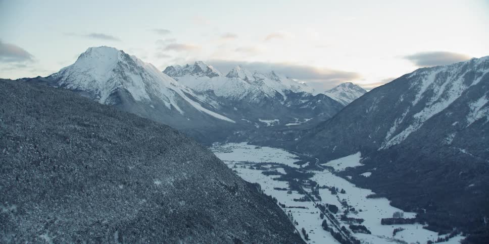 The valley ahead is covered in snow by the mountains