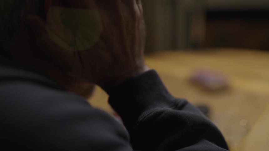 The man rubs his face leaning over the table