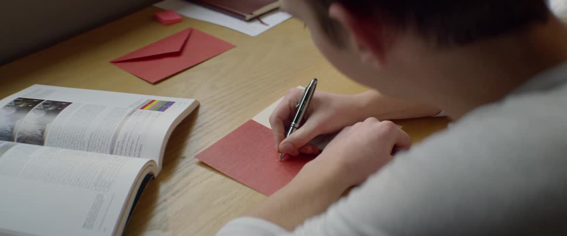 A young man writes in a greeting card