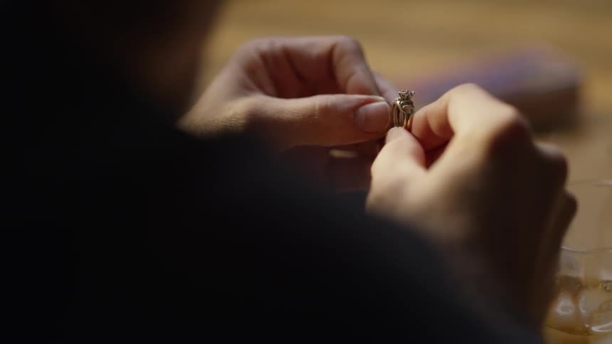 A man holds a gold ring in his hands