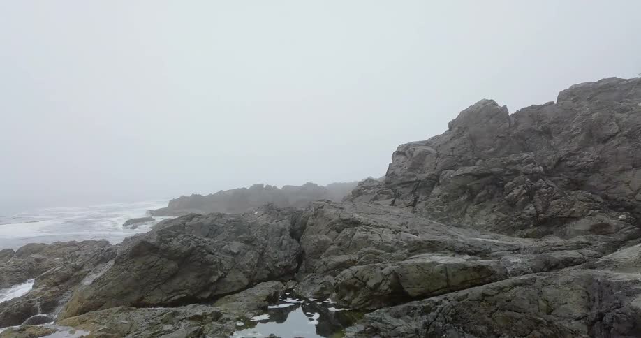 The waves crash against the tall rocks on the shore