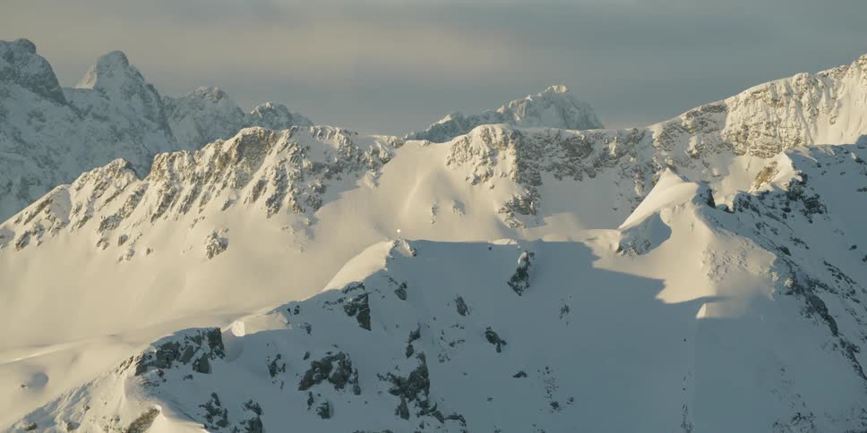 Snow covered mountains stand tall under a cloudy blue sky