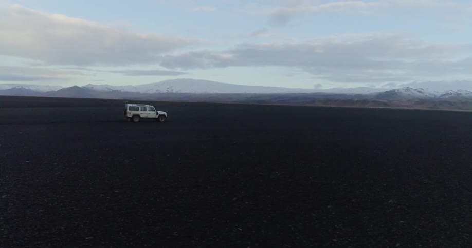 White vehicle travels over the land under a blue sky