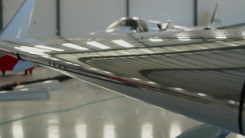A private airplane is sitting idle in a hangar in daylight