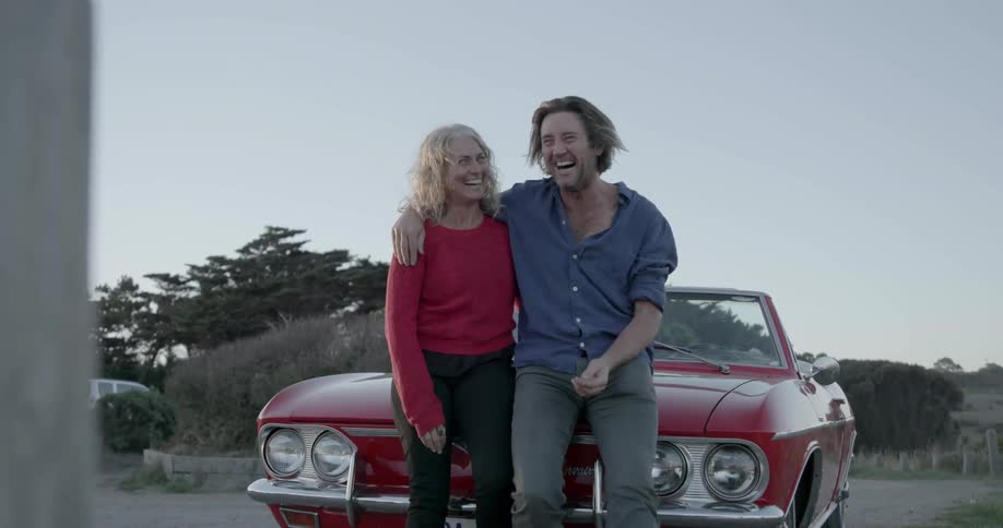 The man and woman sit on the car together