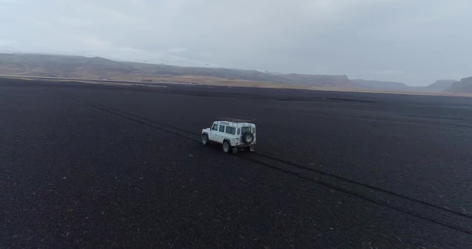 White jeep drives across flat plains