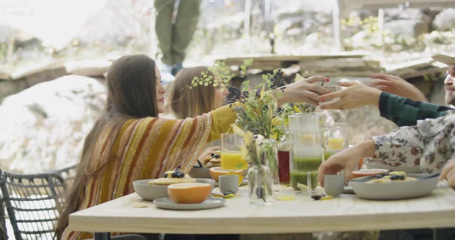 Group of people are eating lunch outside at table on windy day