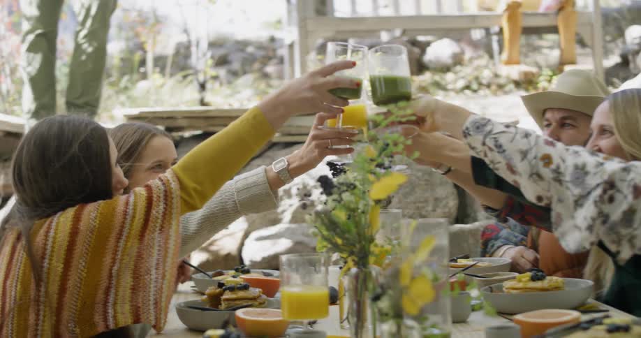 Men and women touch glasses at a table outside