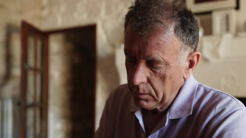 Elderly man sitting in a room looking down